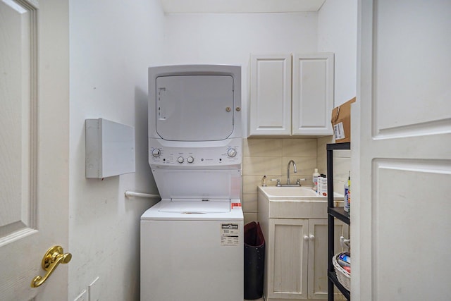 washroom with a sink, stacked washing maching and dryer, and cabinet space