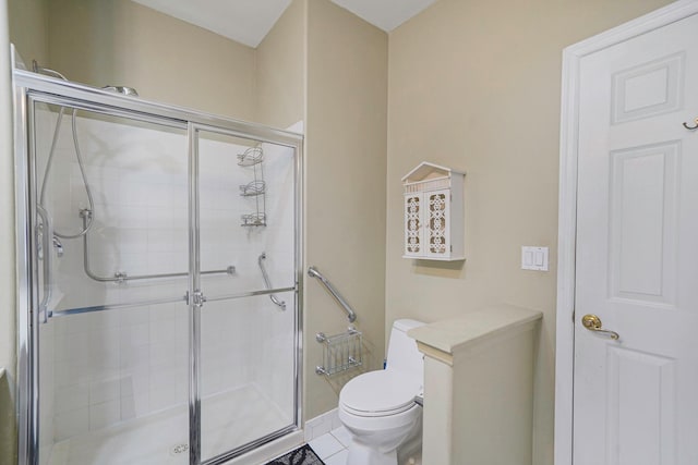 bathroom with tile patterned flooring, baseboards, a shower stall, and toilet