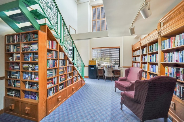 living area featuring wall of books, rail lighting, and carpet floors