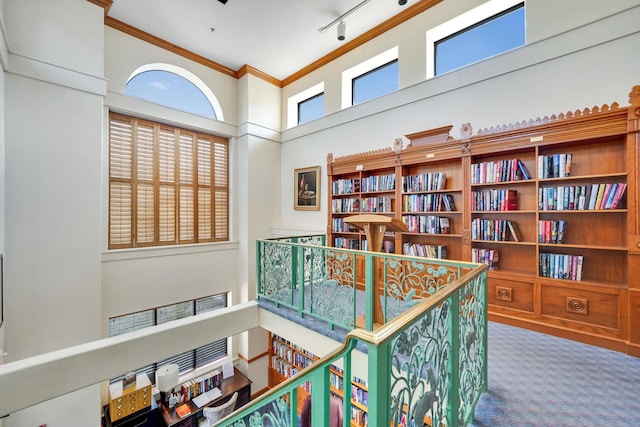 hallway featuring ornamental molding, carpet flooring, a towering ceiling, and track lighting