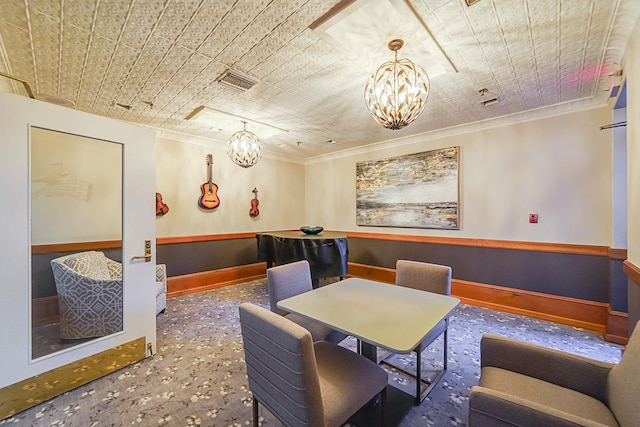 carpeted dining space with crown molding, visible vents, a notable chandelier, and baseboards