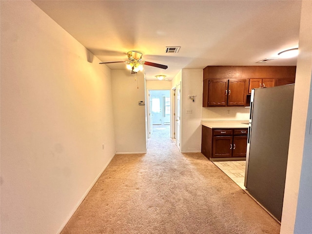 kitchen featuring light countertops, light colored carpet, a ceiling fan, freestanding refrigerator, and baseboards