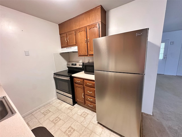 kitchen featuring brown cabinets, light countertops, appliances with stainless steel finishes, a sink, and under cabinet range hood