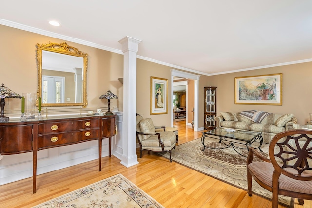 living room featuring ornamental molding, decorative columns, and wood finished floors