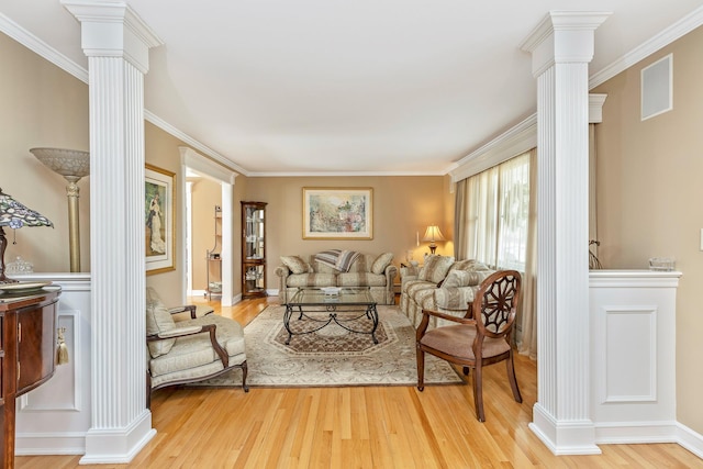 living area with ornamental molding, decorative columns, and light wood-style floors