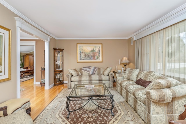 living room featuring decorative columns, ornamental molding, light wood-style flooring, and baseboards