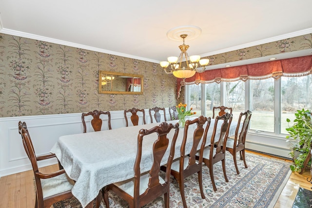 dining room featuring ornamental molding, wainscoting, a notable chandelier, and wallpapered walls