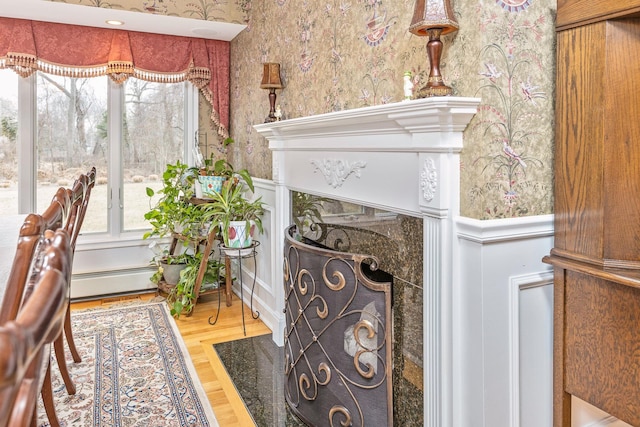 room details featuring a fireplace with flush hearth, wood finished floors, wainscoting, and wallpapered walls