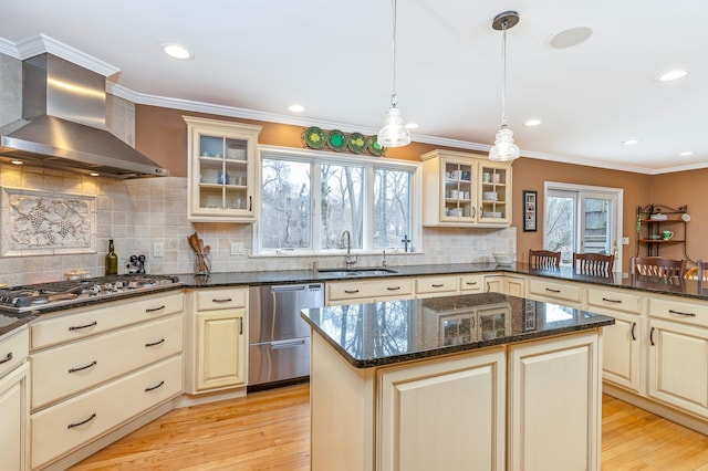 kitchen featuring appliances with stainless steel finishes, a sink, wall chimney range hood, and ornamental molding