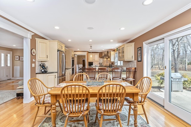 dining room featuring light wood finished floors, crown molding, and recessed lighting