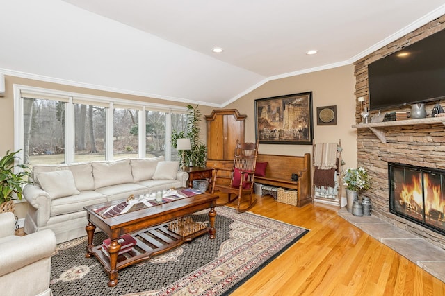 living room featuring lofted ceiling, a stone fireplace, recessed lighting, wood finished floors, and ornamental molding