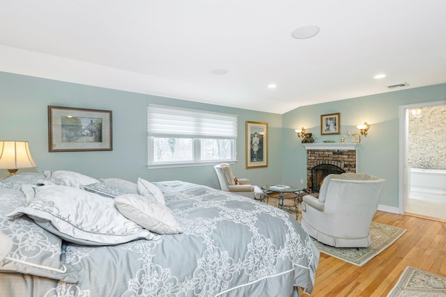 bedroom with visible vents, baseboards, wood-type flooring, a brick fireplace, and recessed lighting