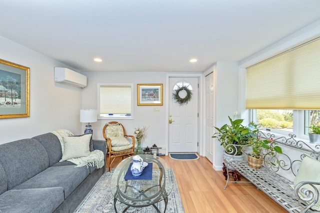 living area with a baseboard heating unit, a wall mounted AC, light wood-type flooring, and recessed lighting