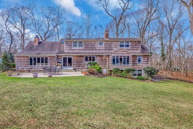 rear view of property featuring a patio area, roof with shingles, a chimney, and a yard