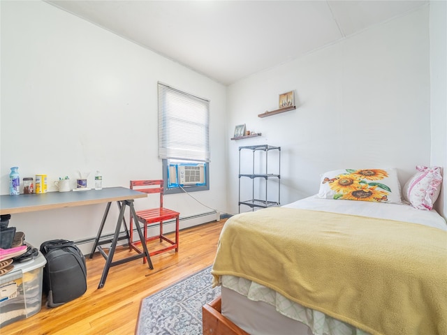 bedroom featuring cooling unit, a baseboard radiator, and wood finished floors
