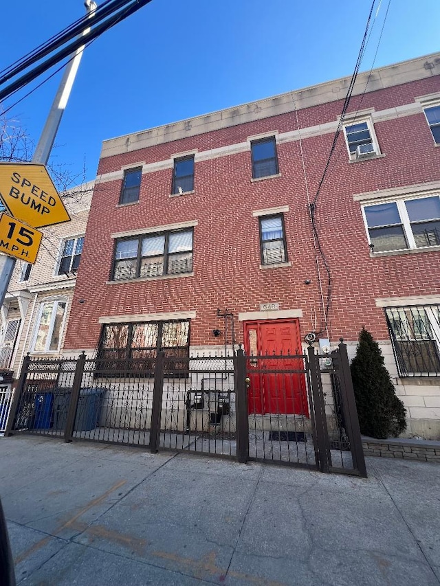 multi unit property with a fenced front yard, a gate, and brick siding