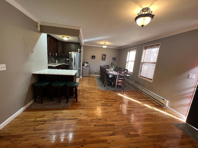 dining room with baseboards, crown molding, baseboard heating, and wood finished floors