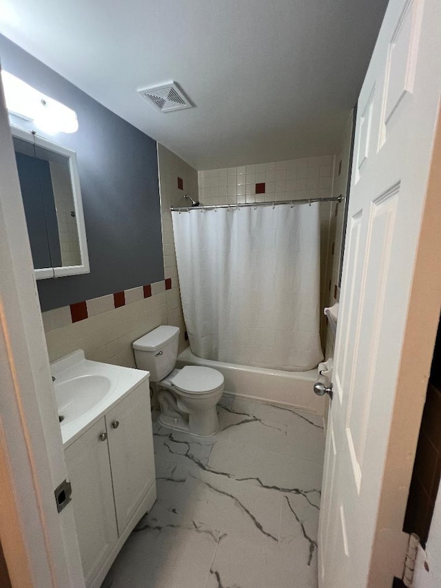 bathroom featuring toilet, vanity, visible vents, tile walls, and marble finish floor