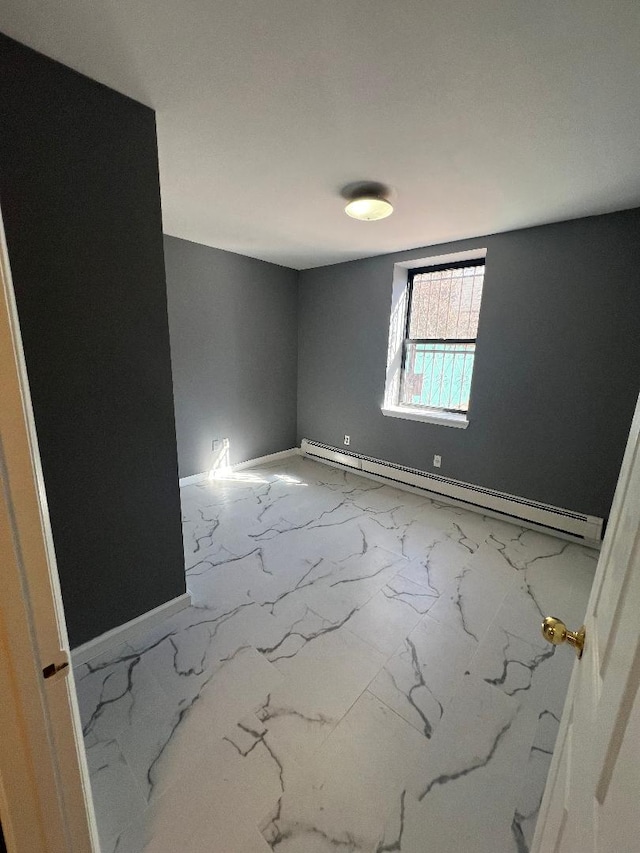 spare room with a baseboard radiator, marble finish floor, and baseboards