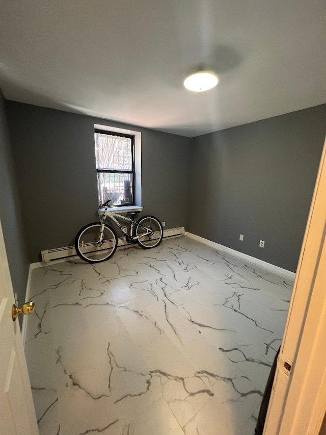 spare room with baseboard heating, marble finish floor, and baseboards