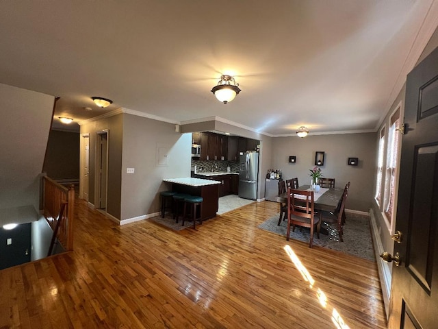 dining space with baseboards, crown molding, and light wood-style floors