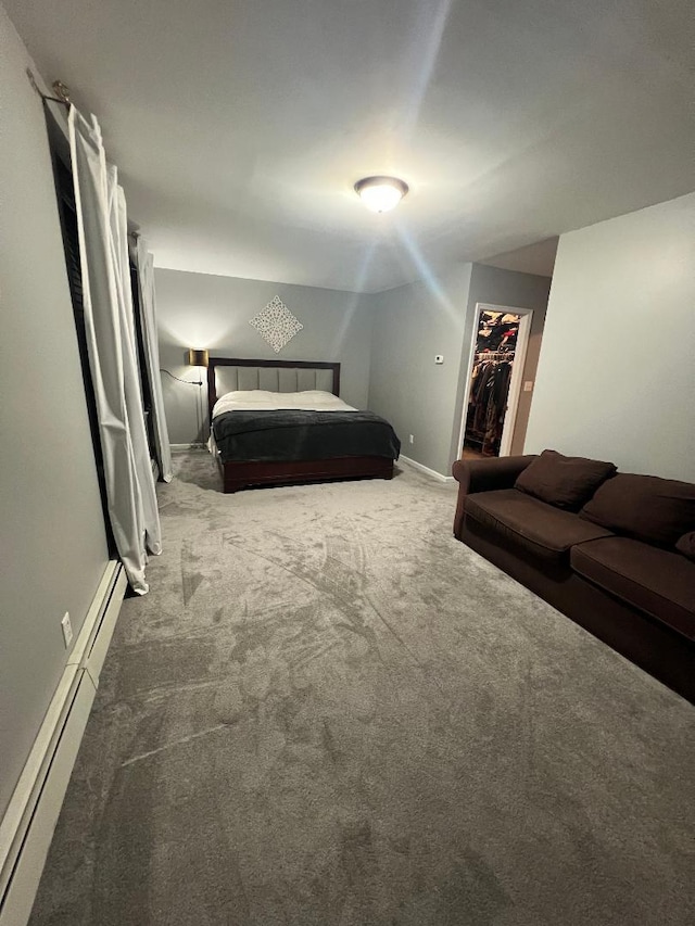 unfurnished bedroom featuring baseboards, a baseboard radiator, a walk in closet, carpet floors, and a closet