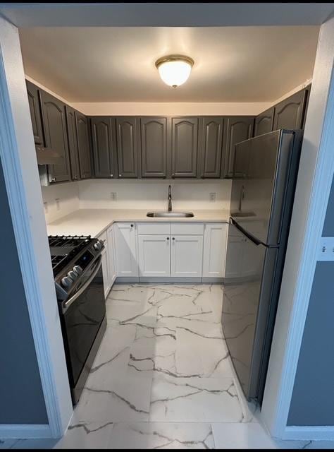 646 Saint Anns Ave, Bronx, NY 10455 - kitchen featuring light countertops, range with gas cooktop, marble finish floor, a sink, and freestanding refrigerator