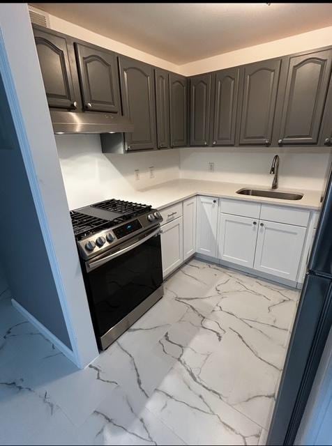 646 Saint Anns Ave, Bronx, NY 10455 - kitchen featuring light countertops, stainless steel range with gas stovetop, marble finish floor, under cabinet range hood, and a sink