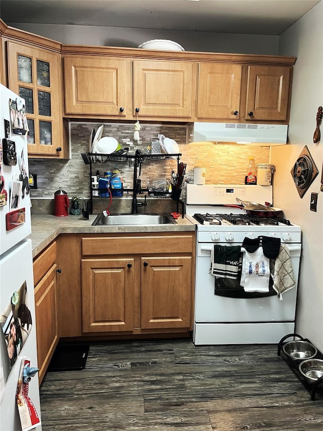 kitchen with white appliances, decorative backsplash, dark wood finished floors, glass insert cabinets, and under cabinet range hood