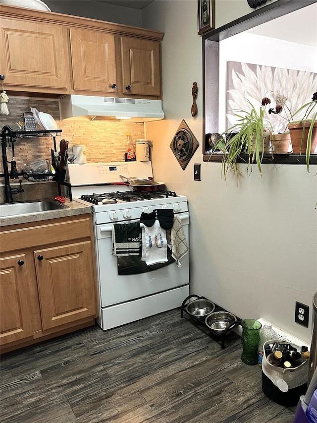 kitchen featuring dark wood-style flooring, under cabinet range hood, backsplash, and white gas range