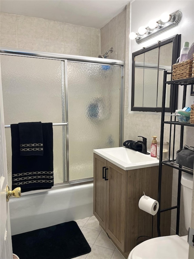 full bath with tile walls, toilet, enclosed tub / shower combo, vanity, and tile patterned floors