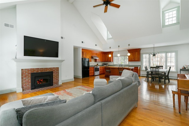 living room with plenty of natural light, light wood-style flooring, a fireplace, and visible vents