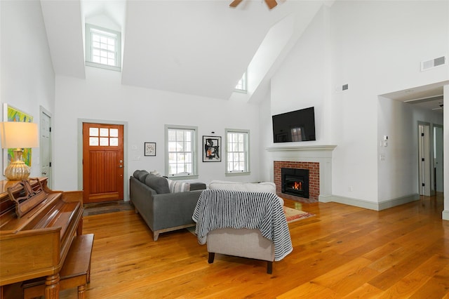 living room with visible vents, baseboards, ceiling fan, light wood-type flooring, and a fireplace