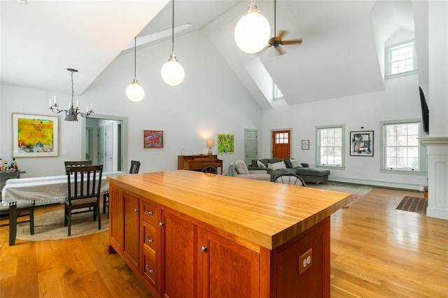 kitchen featuring decorative light fixtures, light wood-style flooring, baseboard heating, wood counters, and ceiling fan with notable chandelier