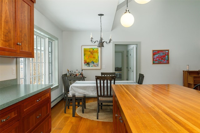 dining space featuring light wood-style floors, a baseboard heating unit, and a notable chandelier