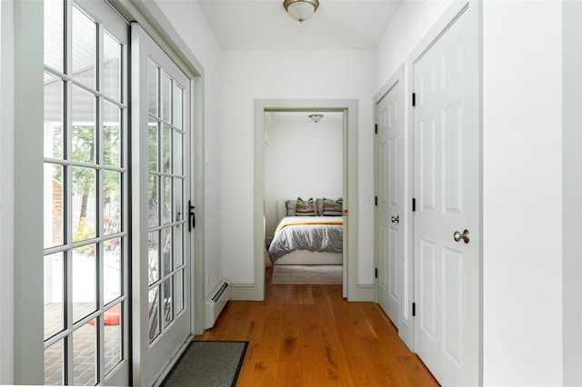 doorway with light wood-style floors, baseboards, and baseboard heating