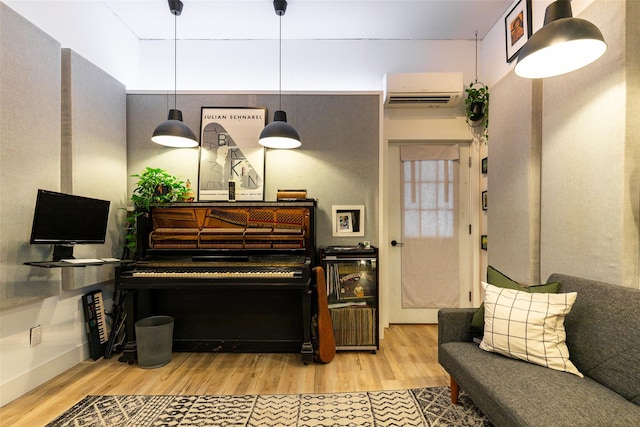 living area with baseboards, wood finished floors, and a wall mounted air conditioner