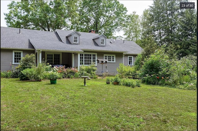 cape cod house featuring roof with shingles and a front lawn