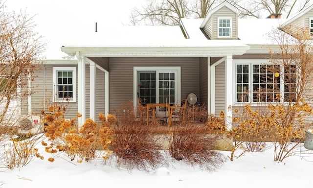 snow covered property entrance with a porch