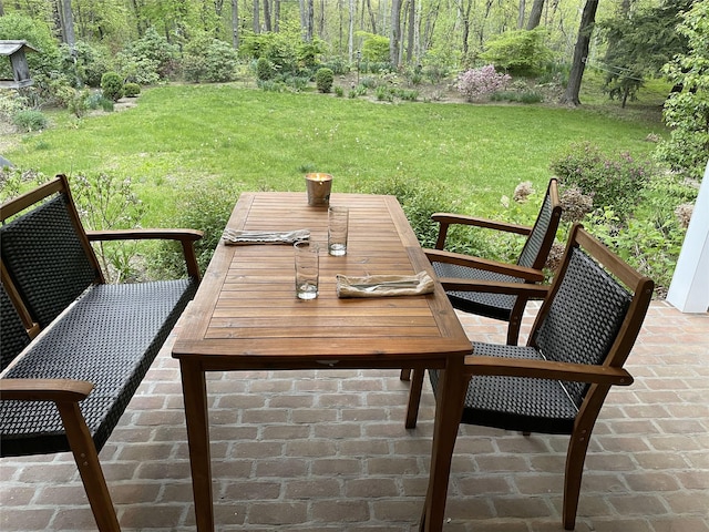 deck with outdoor dining space, a yard, and a view of trees