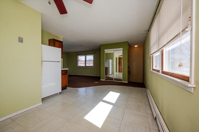 empty room featuring a ceiling fan, light floors, baseboards, and baseboard heating