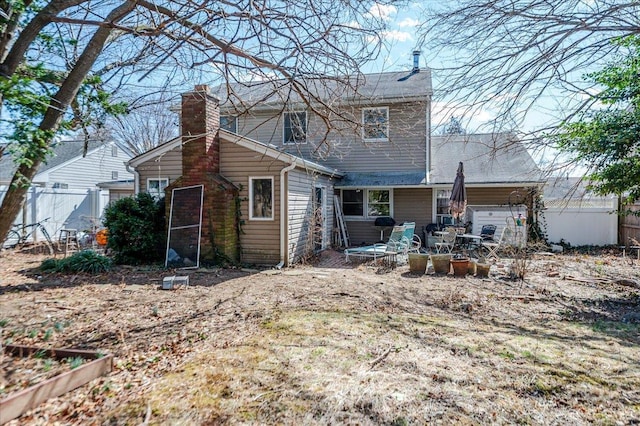 rear view of property featuring a patio area, fence, and a chimney