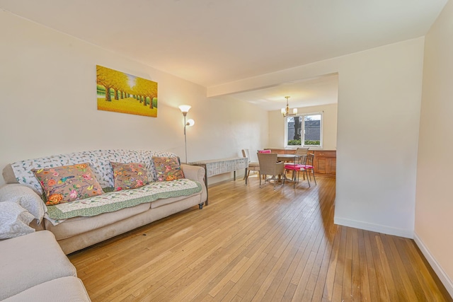 living room with baseboards, a notable chandelier, and hardwood / wood-style floors