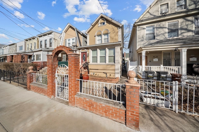 view of front of home with a fenced front yard, a gate, and a porch