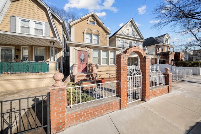 view of front of house with a fenced front yard, a gate, and brick siding