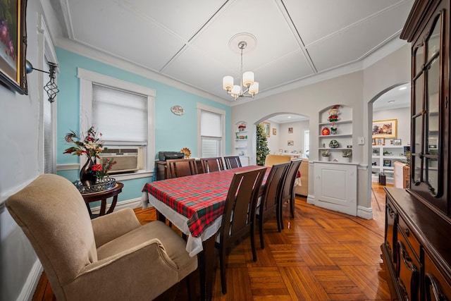 dining area featuring arched walkways, built in shelves, a chandelier, and ornamental molding