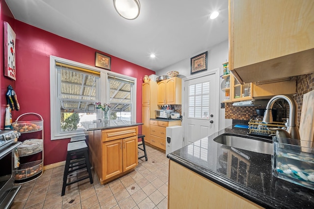 kitchen featuring light tile patterned floors, decorative backsplash, a breakfast bar area, stainless steel range oven, and a sink