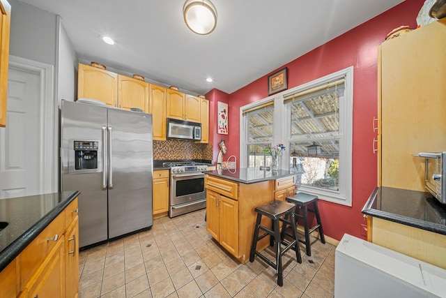 kitchen with light tile patterned floors, a kitchen island, baseboards, appliances with stainless steel finishes, and tasteful backsplash