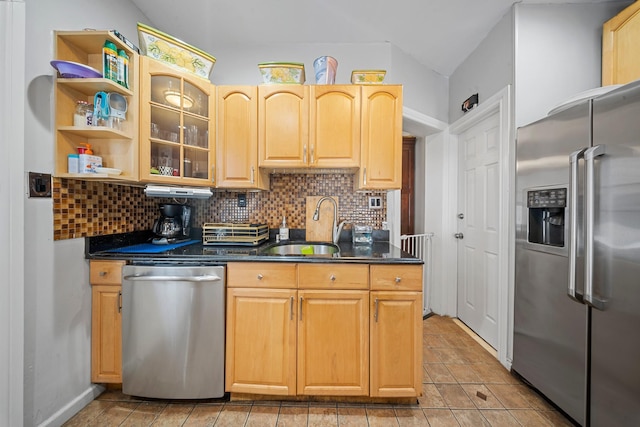 kitchen with decorative backsplash, dark countertops, appliances with stainless steel finishes, glass insert cabinets, and a sink