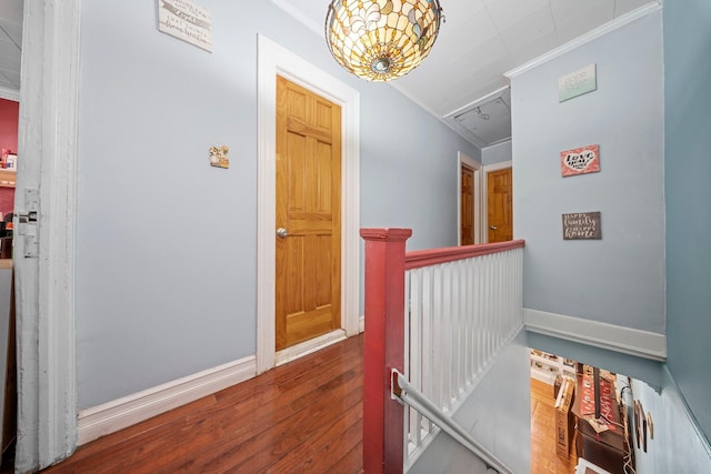 hall with attic access, baseboards, wood finished floors, crown molding, and an upstairs landing